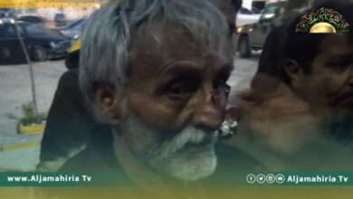 عنصر يرتدي زيا عسكريا يشهر السلاح في وجه المتظاهرين بطبرق