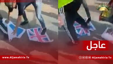 المتظاهرون في الساحة الخضراء بـ طرابلس يدوسون بأقدامهم أعلام دول حلف الناتو التي تدخلت في ليبيا عام 2011.